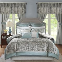 a bed in a bedroom with blue and white comforter set on top of it