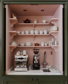 an open cabinet with coffee maker and cups on it