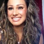 a woman with long curly hair smiling at the camera