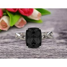 a black diamond ring sitting on top of a table next to pink roses and tulips