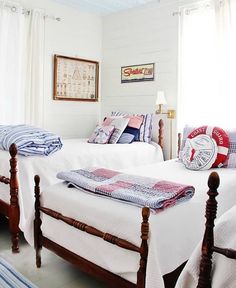 two twin beds in a white bedroom with blue and red pillows on the bedding