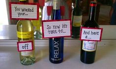 three wine bottles with signs attached to them sitting on a counter next to two empty wine bottles