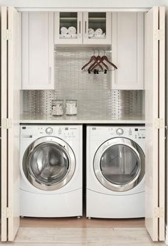 a washer and dryer in a small laundry room with white cabinetry on the wall