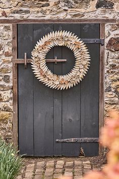 a door with a wreath hanging on it's side in front of a stone building