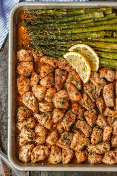 chicken and asparagus on a sheet pan with lemon wedges next to it