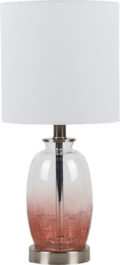 a glass lamp with a white shade on top and a silver base, sitting on a table