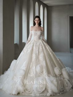 a woman in a wedding dress with long sleeves and flowers on the skirt is posing