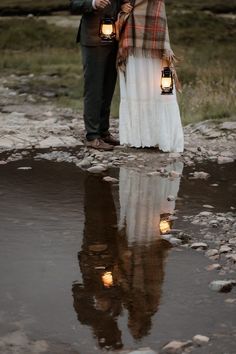 a man and woman standing next to each other holding candles in their hands with the lights on