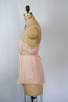 "Vintage 1920s pink silk crepe embroidered floral lace chemise Beautiful lace inset neckline with a sweet ribbon flower Pick stitch embroidery detail on front bust line and more beautiful lace Lace trimmed hem Fabric tie that is attached at back waist and can be worn tied around waist or in a simple bow at back Silk ribbon straps Crotch has been undone so it can be worn as a camisole Pull on MEASUREMENTS: taken flat Fits like a Small Bust: up to 36\" Waist: up to 38\" Hips: up to 46\" Strap Leng Pink Silk Spaghetti Strap Camisole, Pink Lace Trim Slip Dress For Daywear, Feminine Pink Silk Camisole, Pink Lace Trim Slip Dress For Wedding Night, Delicate Fitted Summer Sleepwear, Pink Delicate Lace Sleepwear For Summer, Pink Summer Camisole With Delicate Lace, Summer Pink Lace Camisole, Summer Pink Camisole With Delicate Lace