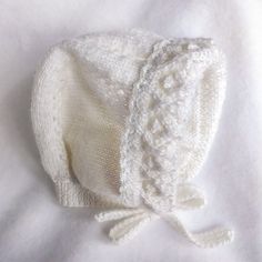 a white knitted hat laying on top of a bed