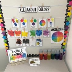 an assortment of colors are displayed on the wall in front of a table with markers