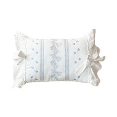 a white pillow with ruffled edges and blue flowers on the front, sitting on a white background