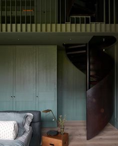 a bed sitting next to a wooden table in a bedroom under a spiral stair case