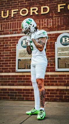 a football player is standing in front of a brick building