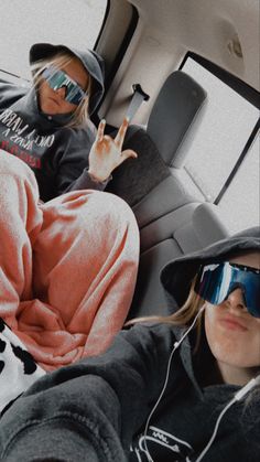 two people sitting in the back of a car with sunglasses on and one person wearing headphones