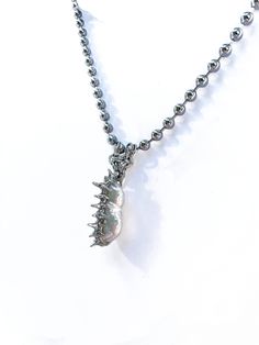 An off white iridescent oblong pearl soldered with soft metal on a 16 in. steel ball chain.  Due to the natural state of the pearl and its handmade nature, the color, shape, and silver solder spheres may vary. Metal Beaded Chain Pearl Necklace As Gift, Unique Silver Beaded Chain Necklace, Gift Pearl Necklace With Beaded Metal Chain, Metal Pearl Necklace With Beaded Chain For Gift, Silver Teardrop Necklace With Beaded Chain, Silver Teardrop Beaded Chain Necklace, Silver Metal Pearl Necklace With Beaded Chain, Silver Minimalist Pearl Necklace, Silver Teardrop Beaded Chain Jewelry