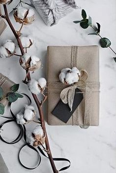 the wrapping paper is wrapped in twine and tied with ribbon, next to cotton flowers