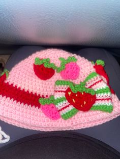 a crocheted hat with strawberries on it sitting in the back seat of a car