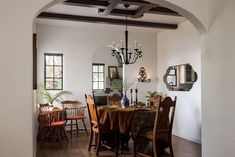 a dining room table with chairs and a chandelier hanging from it's ceiling