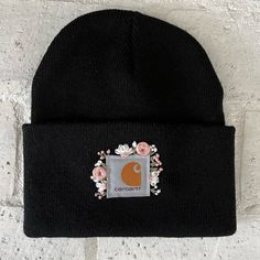 a black beanie with an orange c on the front and white flowers around it