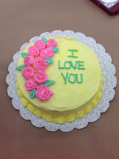 a yellow cake with pink roses on it and the words i love you written in frosting