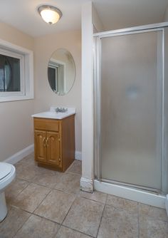 a bathroom with a toilet, sink and shower stall in it's corner area