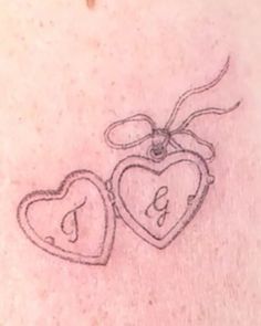 two heart shaped tattoos on the back of a woman's stomach, one with an initial