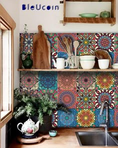 a kitchen with colorful tiles on the wall and wooden shelves above it is a sink