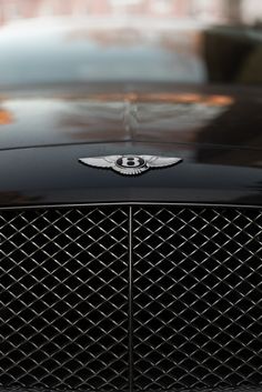 the front end of a black car with a bentley emblem on it's grill