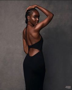 a woman in a black dress posing for the camera with her hands on her head