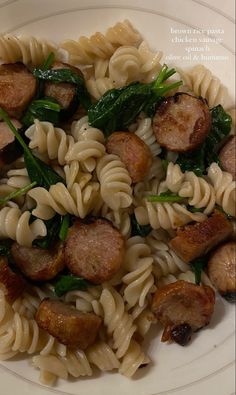 a white plate topped with pasta and sausage