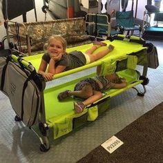 two children laying on top of a green cart