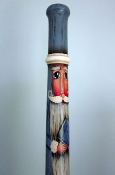 a tall wooden pole with a painted figure on it's side and a hat on top