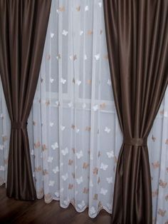 the curtains in this room are brown and white with gold butterflies on them, along with sheer drapes