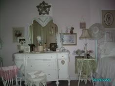 a white dresser sitting next to a bed in a room with pictures on the wall