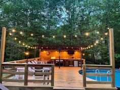 a wooden deck with lights strung over it next to a swimming pool