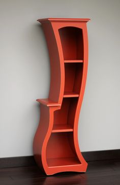 an orange book shelf sitting on top of a hard wood floor next to a white wall