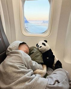 a baby sleeping on an airplane with a stuffed panda bear