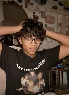 a young man with curly hair wearing glasses