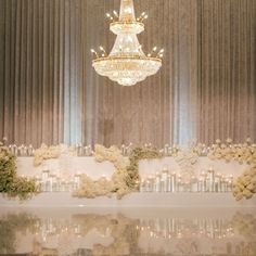 a chandelier hanging from the ceiling above a table with flowers and candles on it