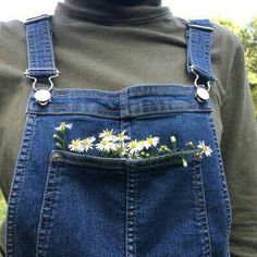 a person wearing overalls with daisies in the pocket