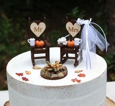 a wedding cake decorated with two chairs and fall leaves on the top is mr and mrs