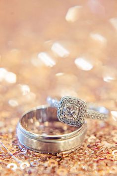 two wedding rings sitting on top of each other in the middle of glittery floor