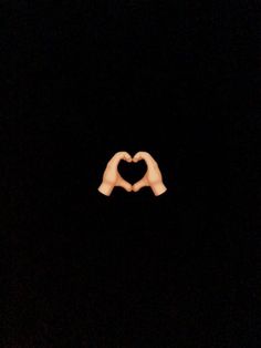 two hands making a heart shape in the dark