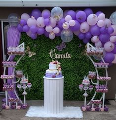 a cake and cupcakes are on display under balloons