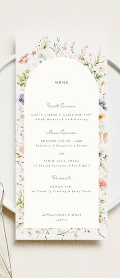 the floral menu card is shown on top of a white plate with silverware next to it