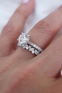 a woman's hand with an engagement ring and wedding band on her left hand