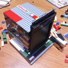 a computer case made out of legos on a table with other toys around it