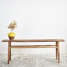 a wooden bench with a yellow vase on it