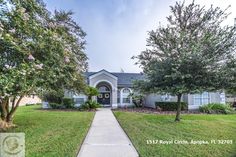 a house that is in the grass with some trees and bushes around it's front yard